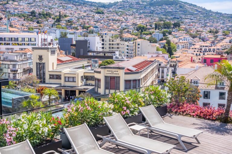 Rooftop garden terrace with sun loungers overlooking city and hills.