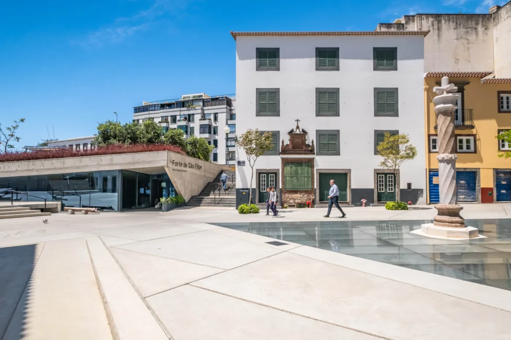 Modern plaza with historical white building and decorative fountain.